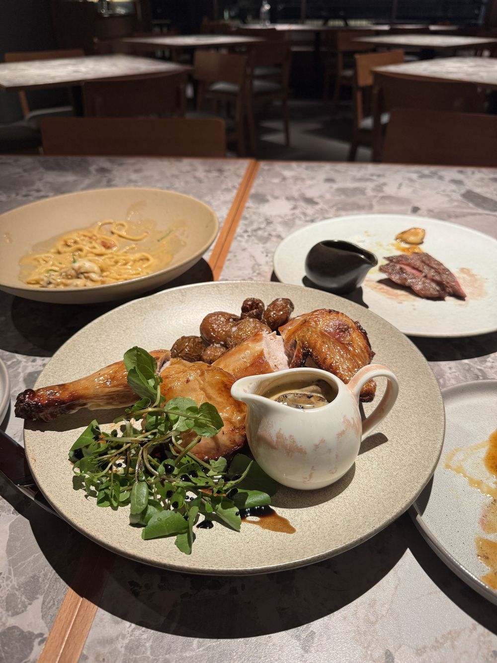Roast chicken with confit potatoes, watercress and a jug of gravy in the STEKA dining room