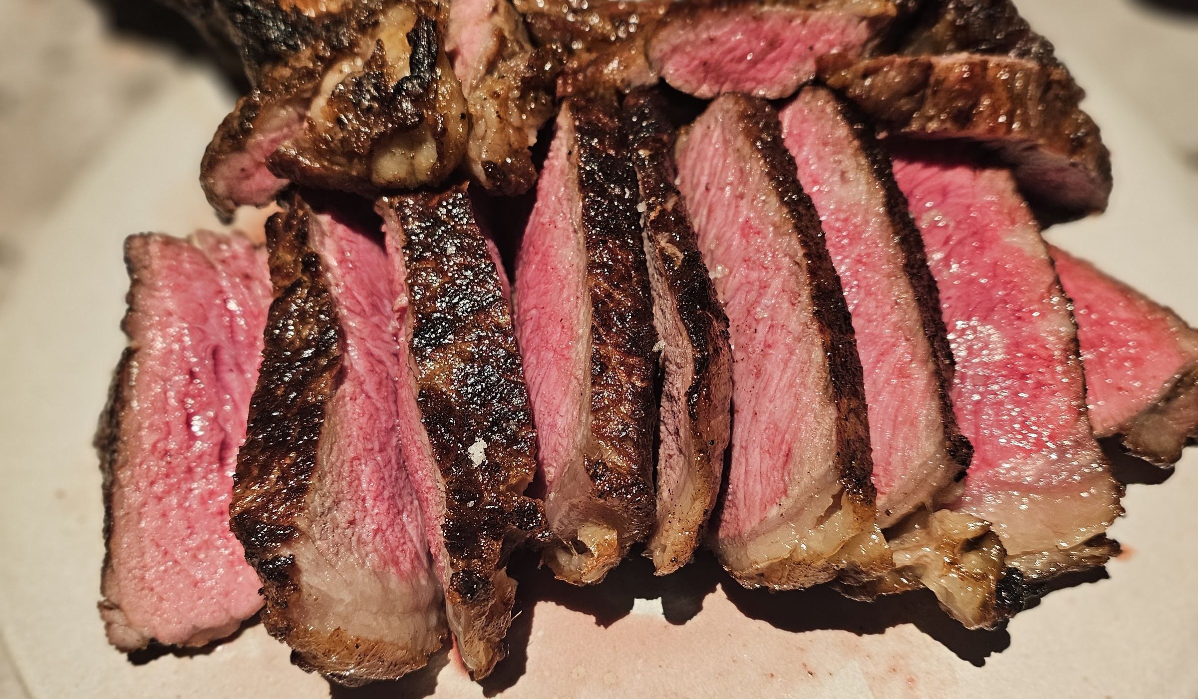 Sliced bone-in ribeye cooked medium rare, served with condiments at STEKA Grill House