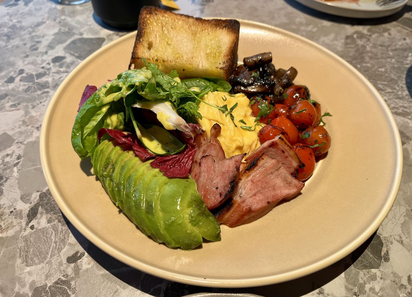 Grilled plate with eggs, avocado, blistered tomatoes, mushrooms and toasted bread